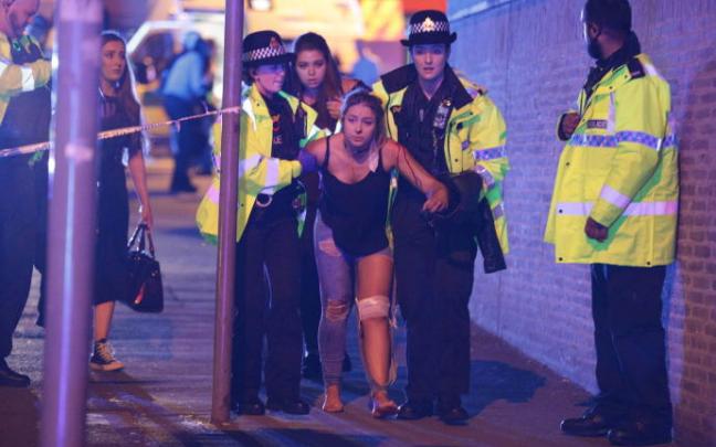 Policías ayudan a una joven herida en las cercanías del Manchester Arena, el 22 de mayo de 2017.