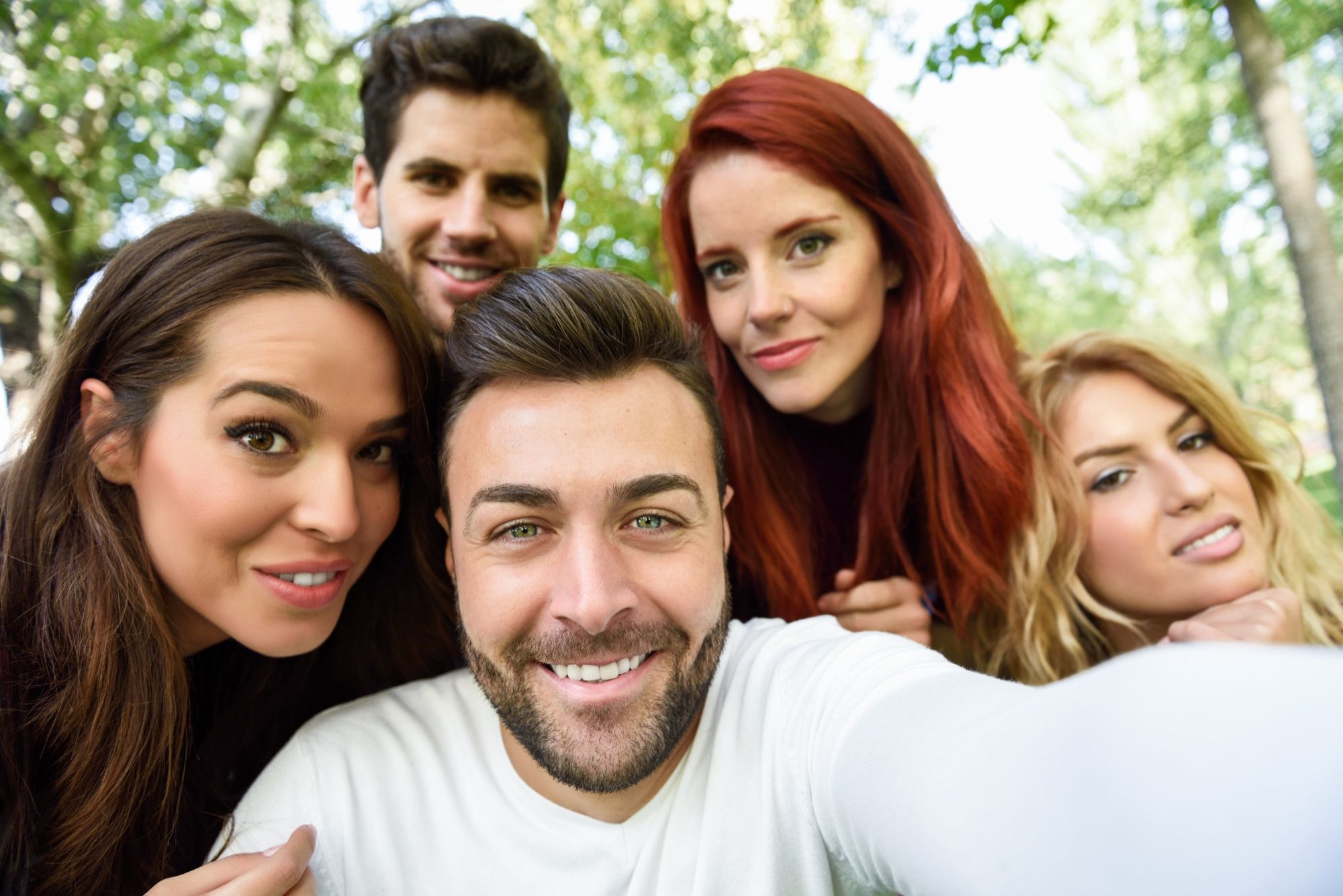 Chicos y chicas se hacen un selfie en un parque.