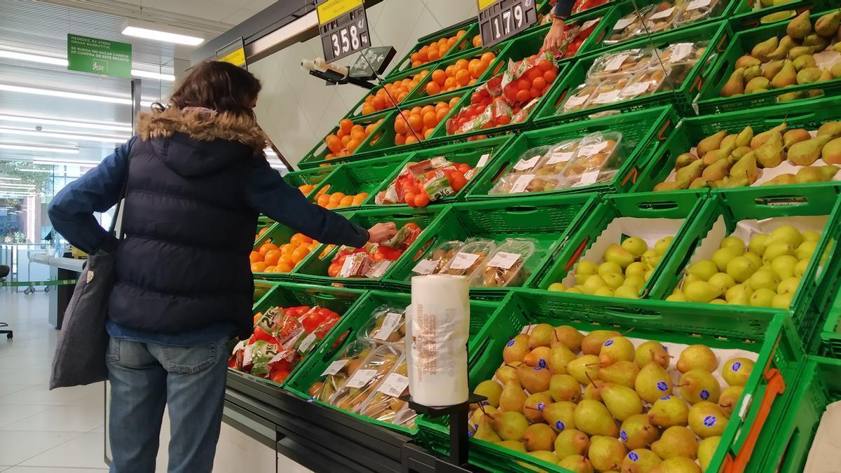 Una mujer escoge fruta en un supermercado.