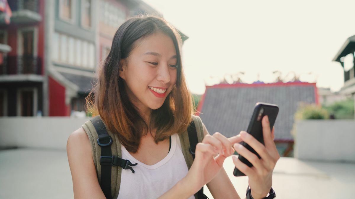 Una joven viajera logra comunicarse con su familia usando su smartphone.