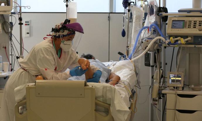 Una enfermera atiende a un paciente con respirador ingresado por coronavirus