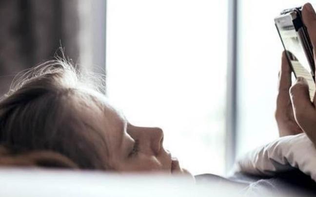 Una menor consulta su tel&eacute;fono m&oacute;vil.