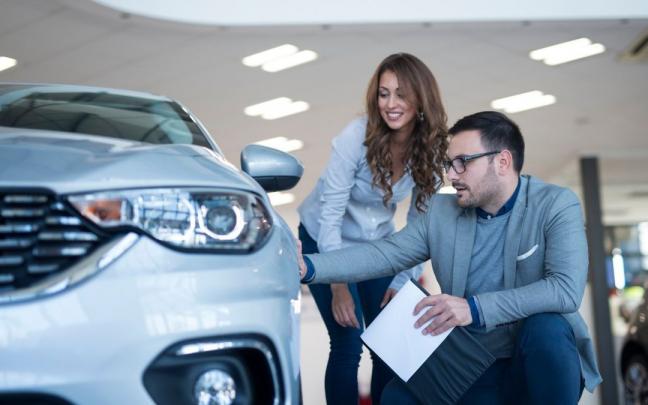 Dos personas observando un vehículo en el concesionario.
