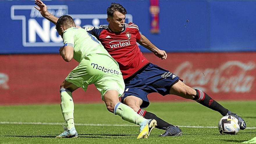 Ante Budimir trata de rematar dentro del área del Getafe con la oposición de un futbolista del equipo rival.