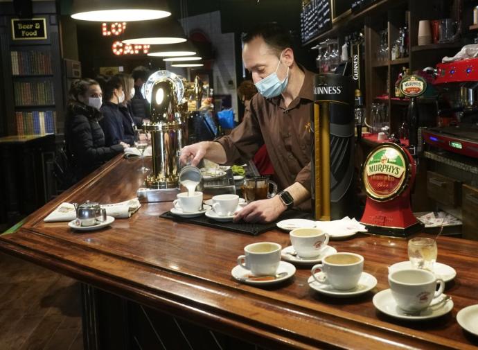 Un camarero sirve un café en el interior de un bar.