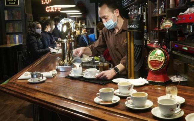 Un camarero sirve un café en el interior de un bar.