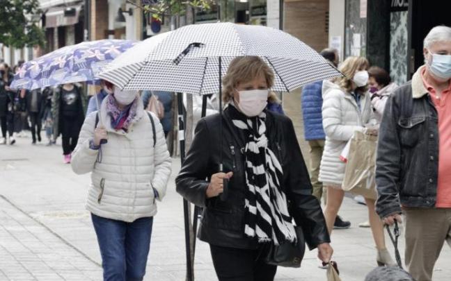 Una persona camina aferrada a su paraguas en Vitoria..