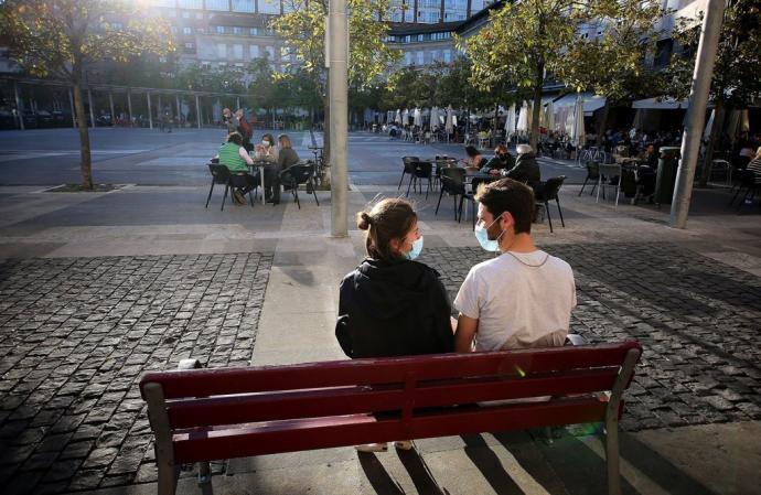 Dos jóvenes hablando en un banco de la plaza de Yamaguchi con la mascarilla puesta.