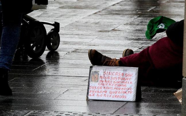 Una persona pide limosna en la avenida Carlos III de Pamplona.