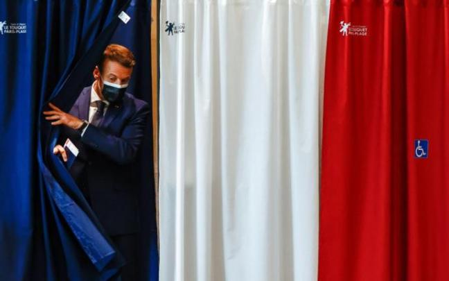 Macron, saliendo de la cabina, con los colores de la bandera francesa, con su papeleta para votar en las elecciones regionales. Macron, saliendo de la cabina, con los colores de la bandera francesa, con su papeleta para votar en las elecciones regionales.