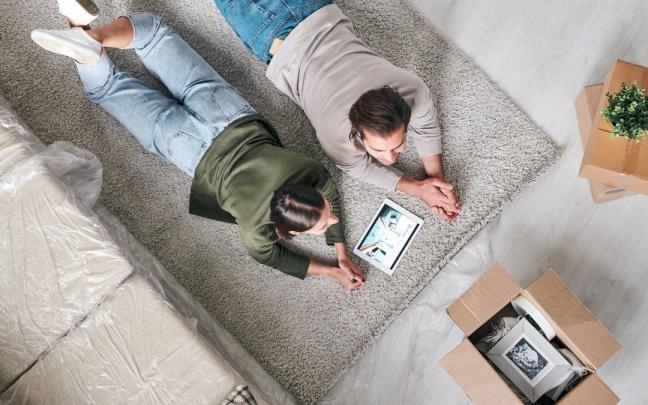 Una pareja lee en su tableta un anuncio de una inmobiliaria.