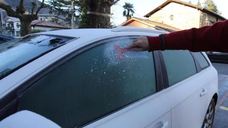 Una persona rasca el coche tras una helada