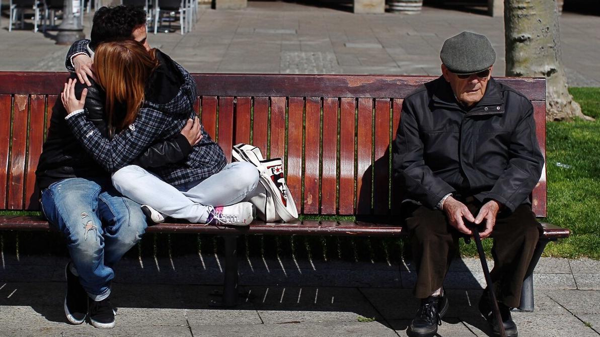 Una pareja de jóvenes se abraza junto a una persona mayor