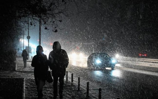 Varias personas pasean por una calle a oscuras de Kiev en plena tormenta de nieve.