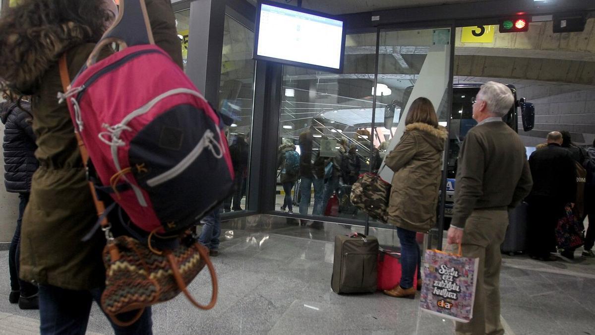 Viajeros y viajeras, consultando una de las pantallas de informaci&oacute;n de la estaci&oacute;n de autobuses de Donostia