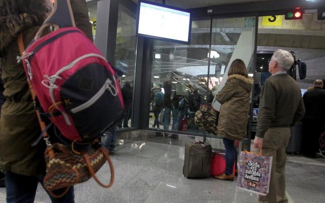 Viajeros y viajeras, consultando una de las pantallas de informaci&oacute;n de la estaci&oacute;n de autobuses de Donostia