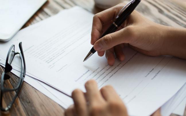 Una persona firma un documento concreto.