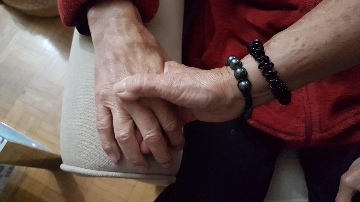 Una mujer coge la mano de una persona con Alzheimer.