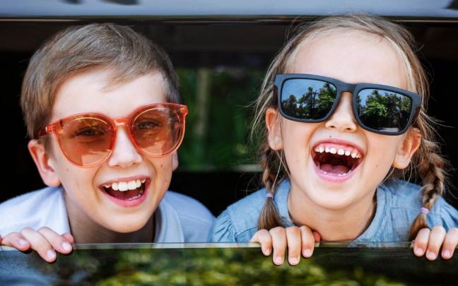 Una pareja de niños sonríe desde la ventanilla del coche, rumbo a su destino vacacional. Una pareja de niños sonríe desde la ventanilla del coche, rumbo a su destino vacacional.