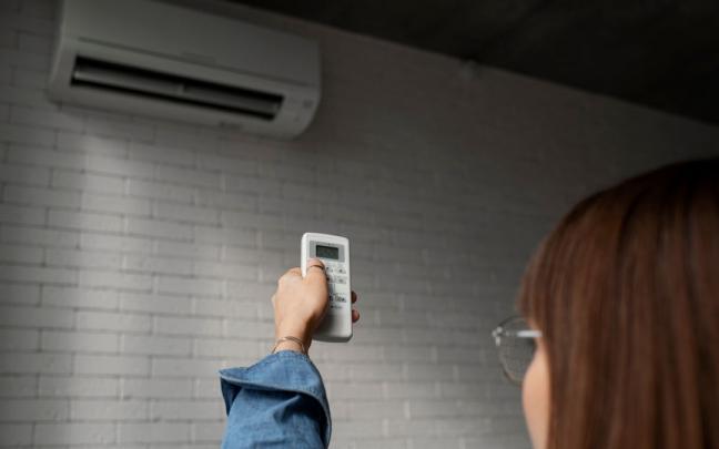 Una mujer regula la temperatura del aire acondicionado. Una mujer regula la temperatura del aire acondicionado.