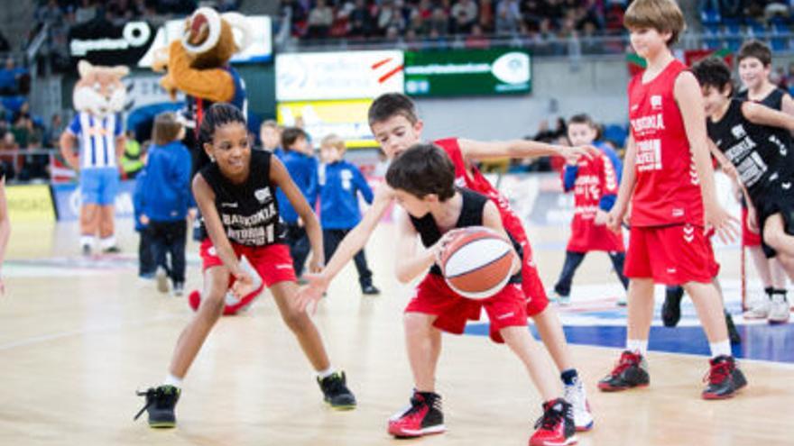 Varios txikis juegan a baloncesto.
