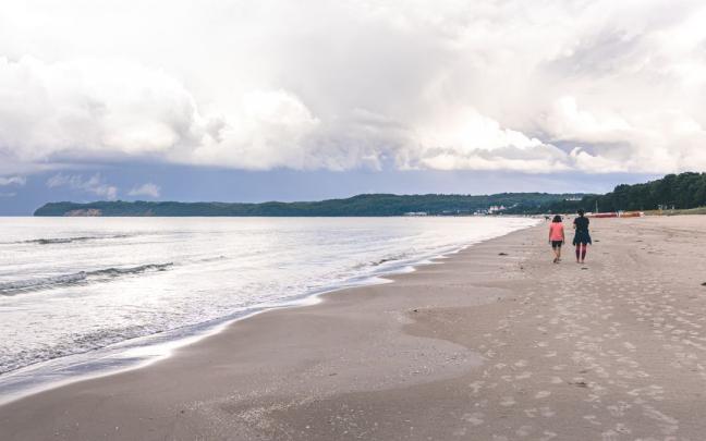 Dos personas pasean por una playa. Dos personas pasean por una playa.