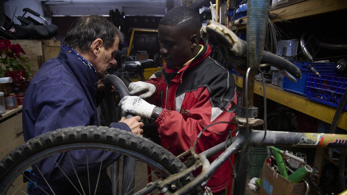 Michael Korang y Jesús Olazarán trabajando en la reparación de una bicicleta.