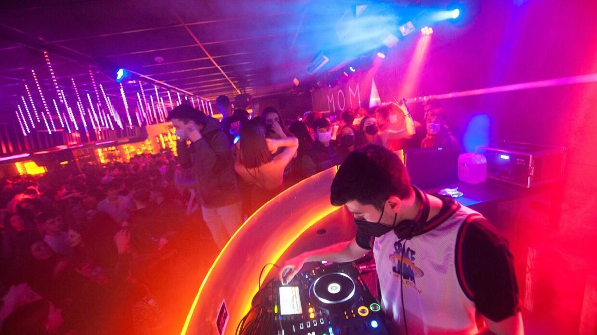 Un joven DJ pinchando en una sala de fiestas abarrotada.