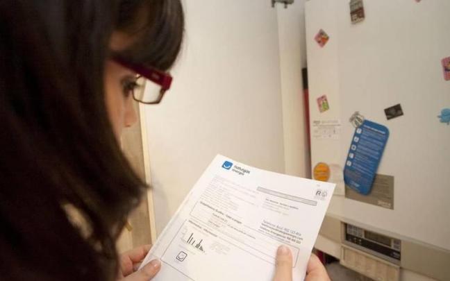 Una persona consulta su factura de gas junto a una caldera.