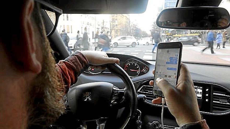 Un conductor consulta su teléfono móvil al volante. | FOTO: P. VIÑAS