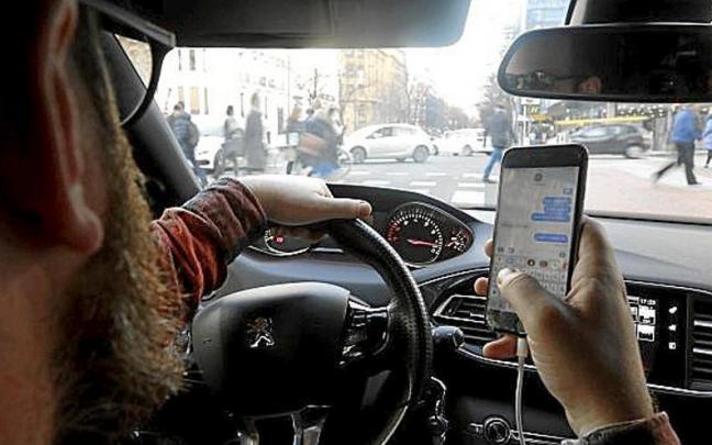 Un conductor consulta su teléfono móvil al volante. | FOTO: P. VIÑAS