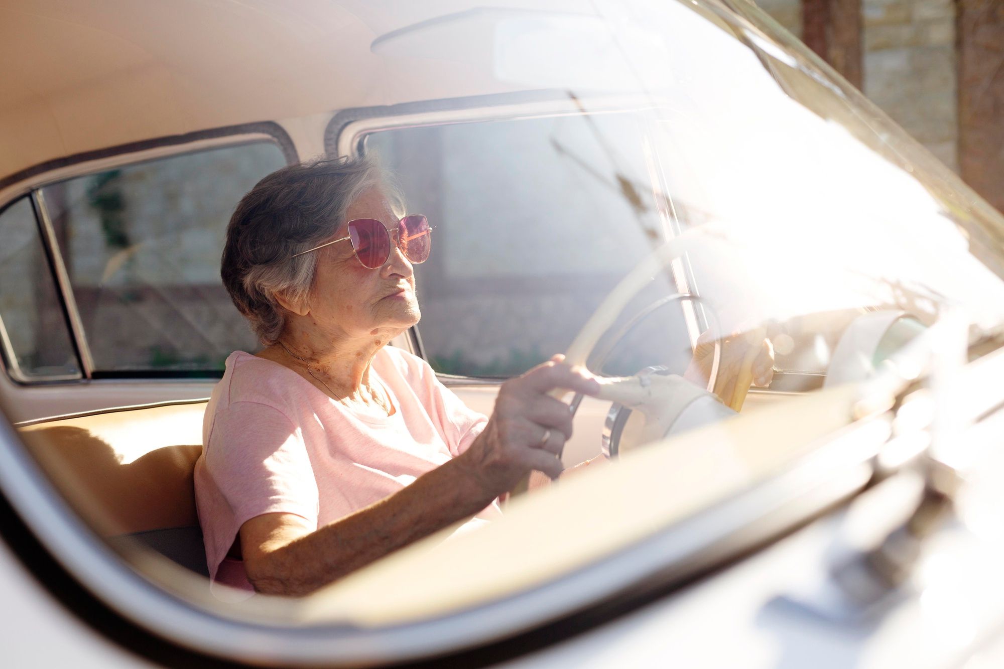Una mujer mayor al volante de un coche antiguo.