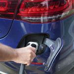 Un hombre reposta su coche electrico