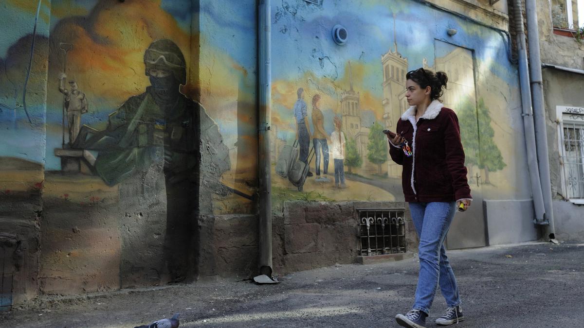 Una joven pasa ayer domingo ante un mural bélico en la ciudad ucraniana de Lviv.