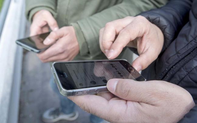 Dos hombres utilizan sendos tel&eacute;fonos m&oacute;viles