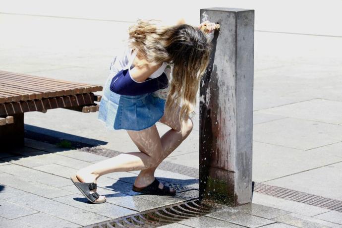 Una niña bebiendo agua de una fuente de Vitoria.