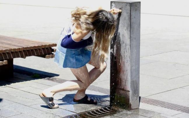 Una niña bebiendo agua de una fuente de Vitoria.