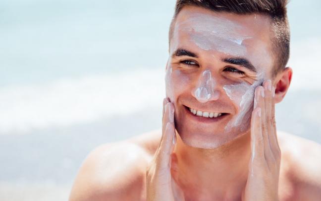 Un joven se da crema en la cara antes de tomar el sol.