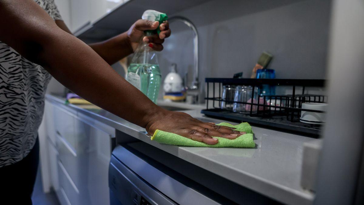 Una empleada de hogar limpia la encimera de la cocina, el día en que han aprobado el paro para estas trabajadoras.