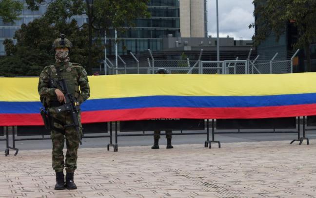 Un militar delante de una bandera de Colombia. Un militar delante de una bandera de Colombia.