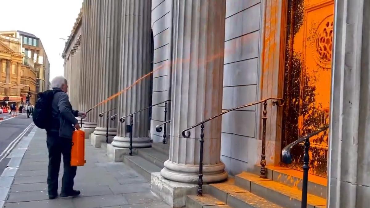 Uno de los activistas rocía con pintura una entrada del Banco de Inglaterra.