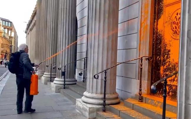 Uno de los activistas rocía con pintura una entrada del Banco de Inglaterra.