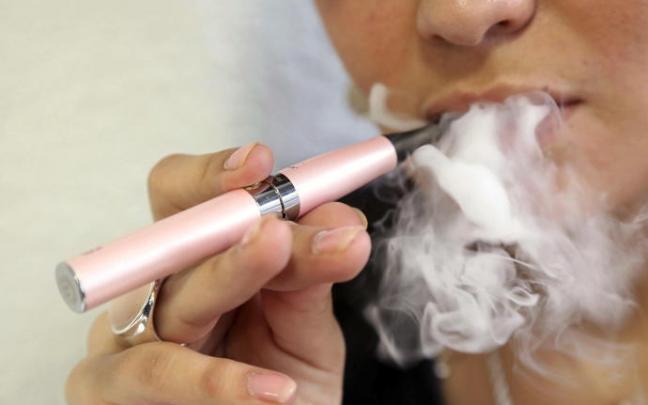 Una mujer fumando con un cigarrillo electrónico. Una mujer fumando con un cigarrillo electrónico.