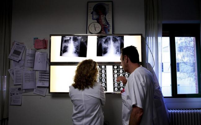 Dos médicos mirando radiografías y un TAC cerebral. Dos médicos mirando radiografías y un TAC cerebral.
