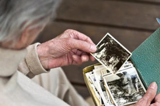 Una persona mayor revisa una caja con fotos antiguas.