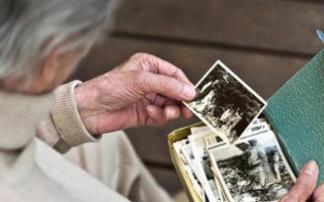 Una persona mayor revisa una caja con fotos antiguas. Una persona mayor revisa una caja con fotos antiguas.
