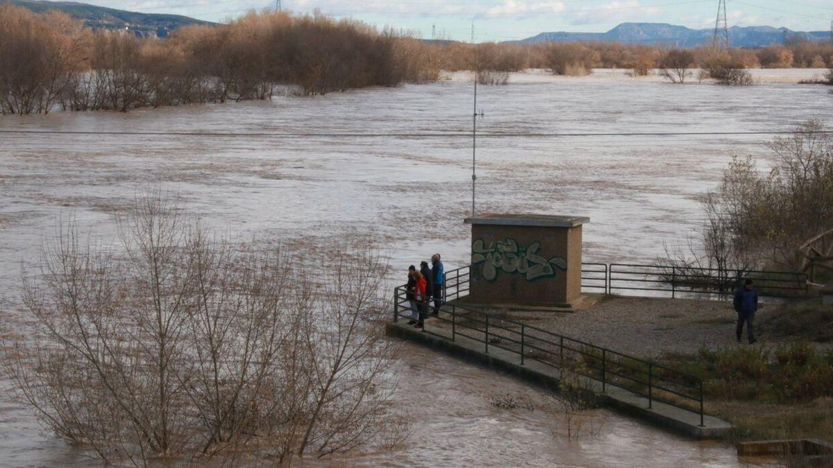 Varias personas observan la crecida del río Ebro junto al medidor.