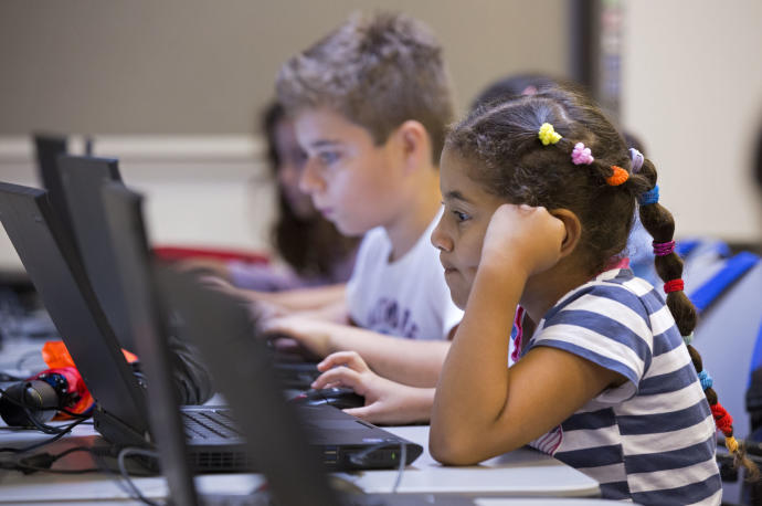 Varios niños trabajan con un ordenador portátil.