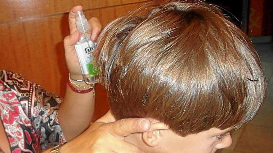 Una madre echa un spray antipiojos a su hijo. | FOTO: E.P.