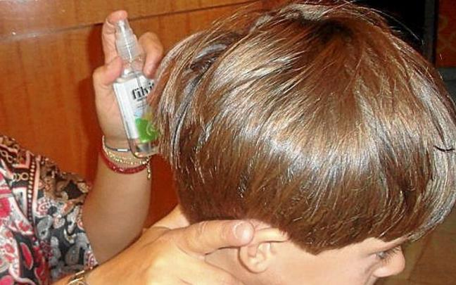 Una madre echa un spray antipiojos a su hijo. | FOTO: E.P.